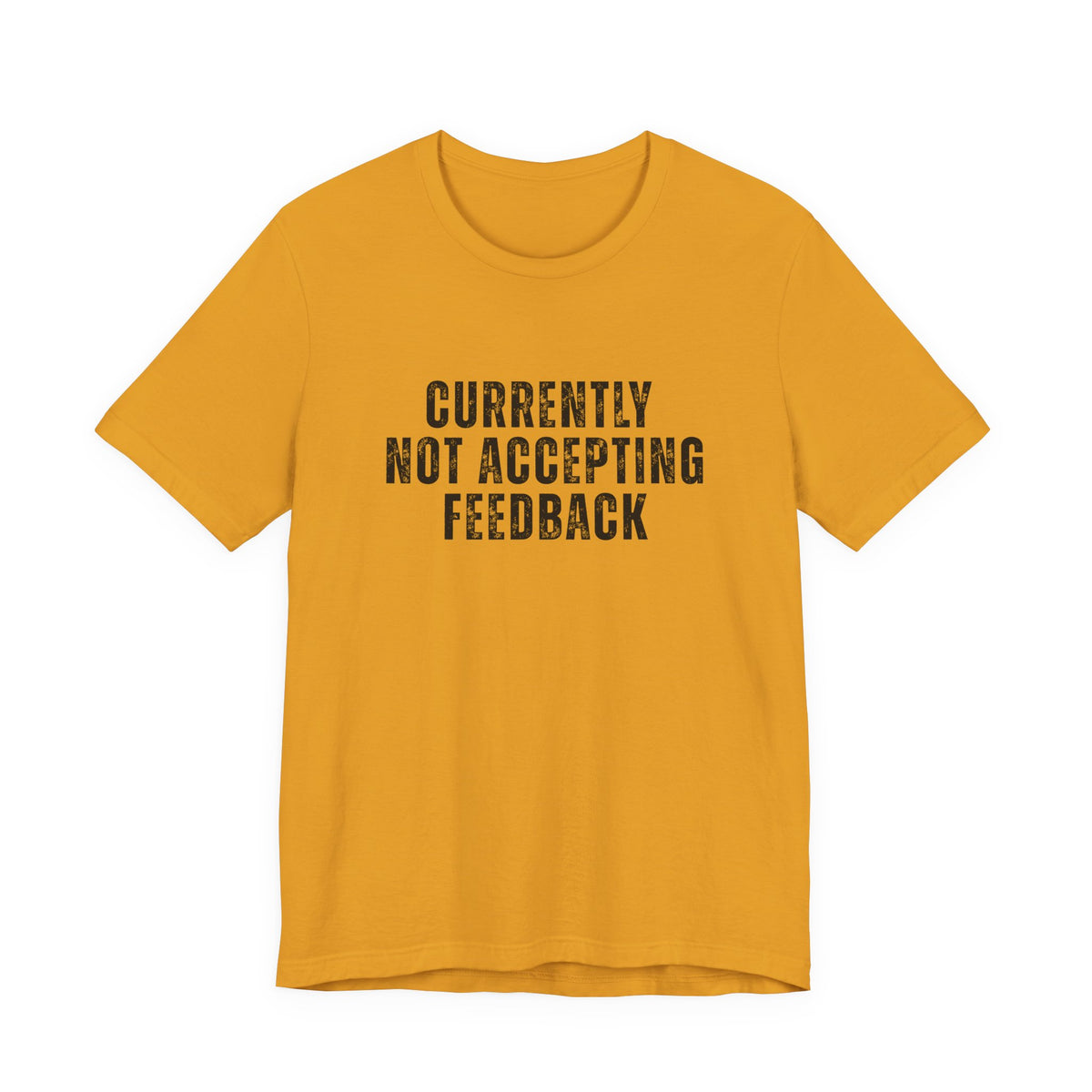 A mustard yellow short-sleeve t-shirt with the text 'CURRENTLY NOT ACCEPTING FEEDBACK' printed in black distressed block letters on the chest, displayed against a solid white background.